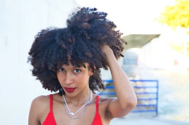 Güzel Afro-Amerikan kadın gülümseyen ve kameraya bakan farklı pozlar veren ve yüzüyle jestler yapan. Kadın kırmızı bir üst ve kırmızı bir ruj sürüyor. Mutluluk kavramı