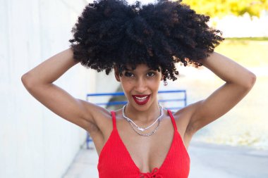 Güzel Afro-Amerikan kadın gülümseyen ve kameraya bakan farklı pozlar veren ve yüzüyle jestler yapan. Kadın kırmızı bir üst ve kırmızı bir ruj sürüyor. Mutluluk kavramı