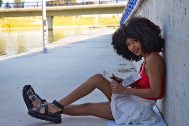 beautiful afro-american woman sitting with her laptop in a park. The girl is a college student. Concept college student