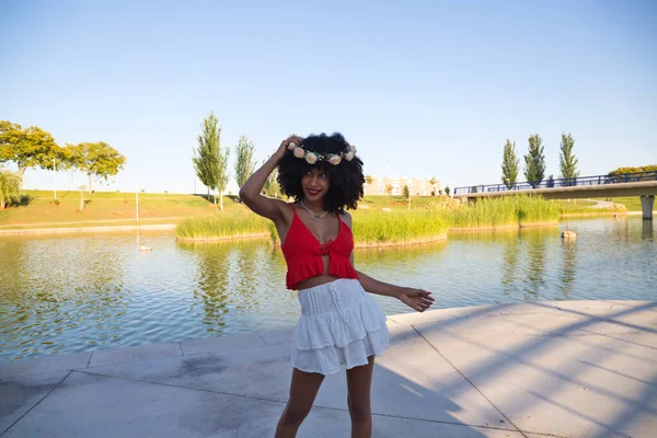 beautiful young afro american woman doing different poses and gestures on camera. She wears in her hair a crown of pink flowers and a red top. Lifestyle concept