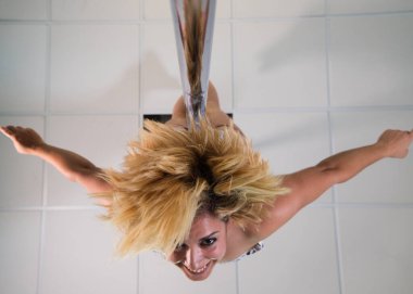 Direk dansçısı ayaklarından sarkan ve kameraya doğru bakan. Model kollarını haç şeklinde açarak aşağıya bakıyordu..