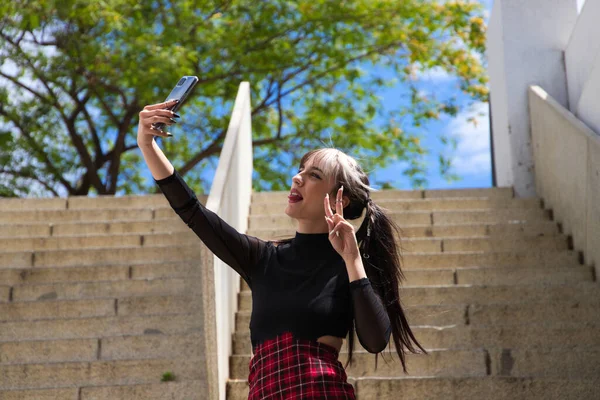 公園の階段で携帯電話で写真を撮るパンクスタイルの若い女の子 テクノロジーと美の概念 — ストック写真
