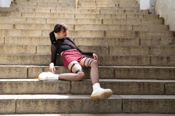 Punk tarzında güzel bir kız merdivende bez bebek Lolita gibi oturuyor..