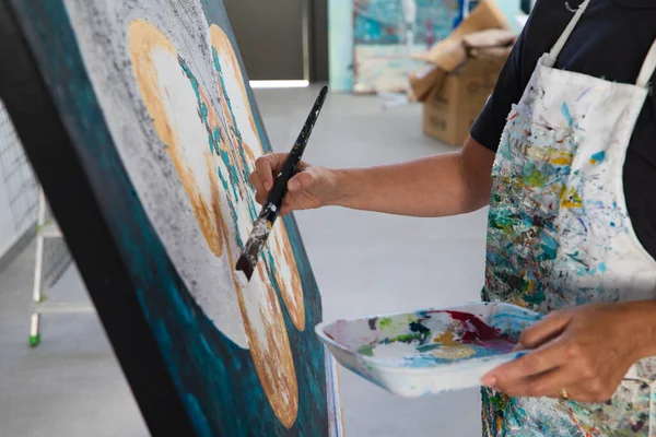 Stüdyoda beyaz bir tuvale kelebek çizen olgun bir kadının ayrıntıları. Sanat ve sanatçı kavramı.