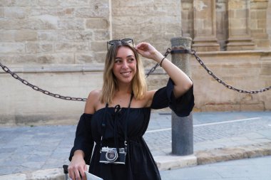 Genç ve güzel sarışın kadın tatillerde kameraya bakarken yüzüyle farklı jestler ve ifadeler yapıyor. Tatil ve seyahat kavramı