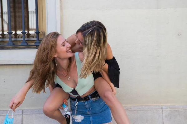 two beautiful young women on holiday. The women are lesbians and one is carrying the other. They are a couple. Concept of equality and diversity.