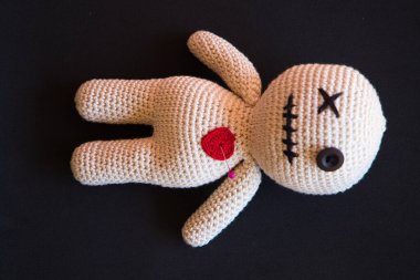 Siyah arka planda uzanan vudu bebeği.