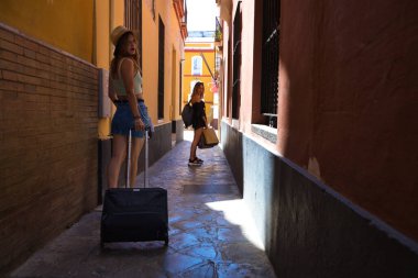 Bir Avrupa şehrinde dar bir sokakta yürüyen iki güzel genç kadın. Kadınlar tekerlekli bavullarını taşıyorlar ve tatillerini geçirecekleri otele gidiyorlar..