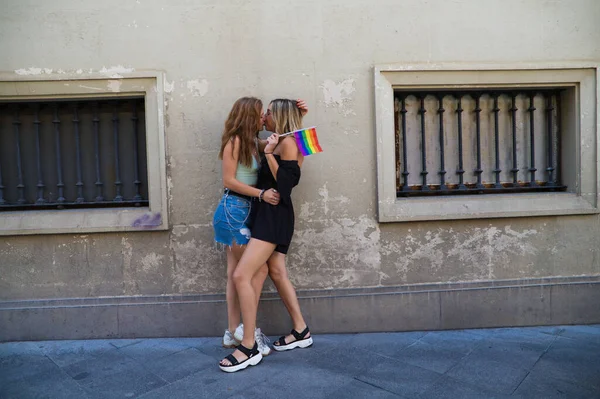 아름다운 여성들은 프라이드 깃발을 껴안고 있습니다 애들은 레즈비언이고 열정적으로 키스를 — 스톡 사진
