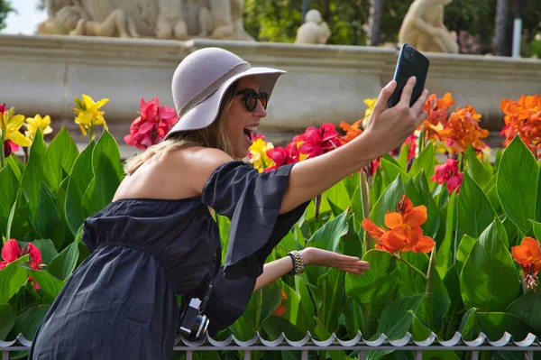 Genç ve güzel bir kadın tatile giderken selfie çekiyor. Kadın kamera, şapka ve güneş gözlüğü takıyor. Tatil, seyahat ve turizm konsepti.