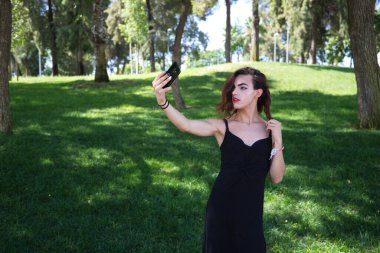 Genç Latin ve transseksüel kadın cep telefonuyla fotoğraf çekiyor. Kadın siyah bir elbise giyiyor. Farklılık, cinsiyet değiştirme ve homoseksüel ifade özgürlüğü kavramları.