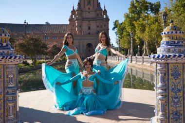 Açık mavi giyinmiş üç güzel dansçı şehir meydanında dans ediyor. Göbek dansı ve göbek dansı konsepti, Afrika folkloru..