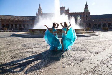 İki genç ve güzel dansçı çeşmenin önünde bir meydanda dans ediyorlar. Açık mavi giyinmişler ve ellerinde beyaz peçeler var. Afrika ve Asya 'dan gelen dünya folklor kavramı.