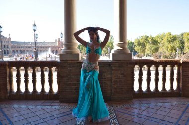 Genç ve güzel dansçı bir fotoğraf çekiminde kameraya poz veriyor. Kadın çok güzel ve geleneksel kıyafetler giyiyor. Güzellik, folklor ve göbek dansı konsepti.