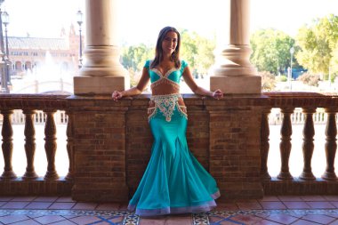 Genç ve güzel dansçı bir fotoğraf çekiminde kameraya poz veriyor. Kadın çok güzel ve geleneksel kıyafetler giyiyor. Güzellik, folklor ve göbek dansı konsepti.