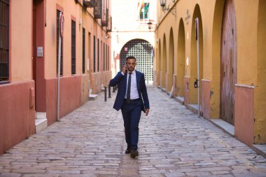 Genç, yakışıklı, koyu renk saçlı, takım elbiseli, kravatlı ve siyah dantelli ayakkabılı bir iş adamı telefonda konuşuyor ve sigara içiyor. Adam çok uluslu bir şirketin yöneticisi.