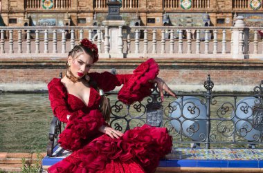 İspanya, Seville 'de bir meydanda fayanslı bir bankta dans eden güzel bir kadın. Kırmızı bir fırfırlı elbise, makyaj ve takma tırnaklar giyiyor. Flamenko, insanlığın kültürel mirası.