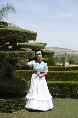 Geleneksel beyaz Endülüs flamenko elbisesi giymiş genç ve güzel bir İspanyol kadın elinde kocaman bir bonsai zeytiniyle dans ediyor.