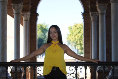 Genç, güzel, koyu renk saçlı, kırmızı elbiseli bir İspanyol kadın Sevilla 'daki Plaza İspanya' daki çeşmesinin önüne atlıyor. Arka planda, su bir gökkuşağı oluşturur.