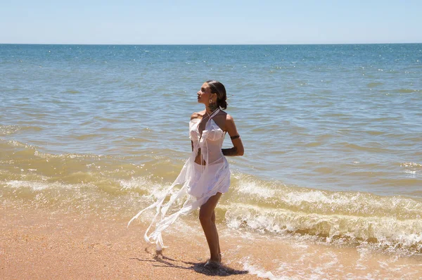 Güneşli bir yaz gününde beyaz giyinmiş güzel bir kadın denizden çıkıyor. Kadının elleri arkada ve Endülüs, İspanya 'da Huelva' da bir plajda duruyor.