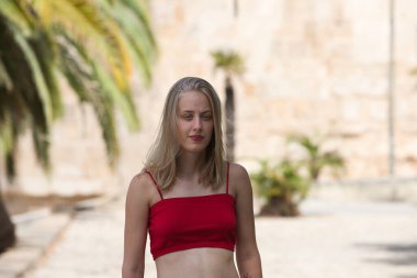 Makyaj yapan, mavi gözlü, kırmızı bluzlu, genç, güzel sarışın bir kadının portresi. Bir yaz günü Seville şehrinde yürüyor. Arka planda Torre del Oro anıtı var.