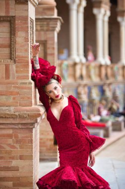 İspanya, Seville 'de bir meydanda, tuğla bir sütuna yaslanmış flamenko dansı yapan güzel bir kadın. O, kırmızı bir fırfırlı elbise giyiyor. Flamenko, insanlığın kültürel mirası.