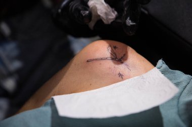 Siyah eldiven takan usta bir dövme sanatçısı müşterisine dövme yapıyor.