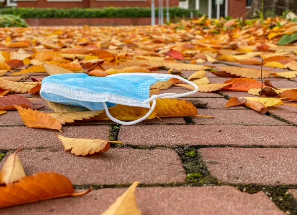 Použitá Lékařská Maska Hozená Cihlový Chodník Mezi Podzimní Listí — Stock fotografie