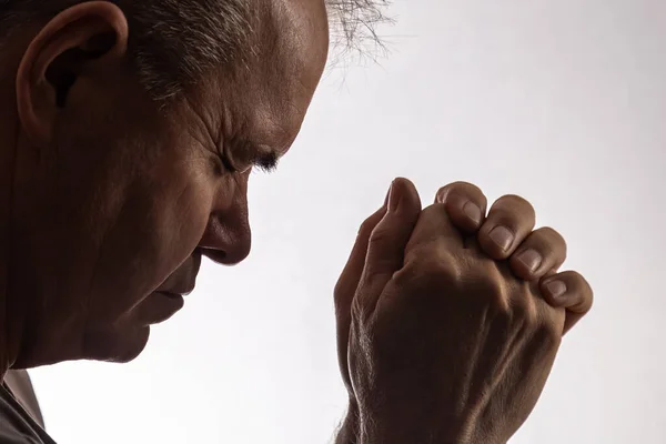 Praying elderly man on a white background.