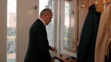 Beyaz bir adam koridorda aynanın önüne koruyucu bir maske takıyor..