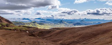 Panoramic Icelandic landscape with volcanic hills, moss valleys, and snowy peaks.