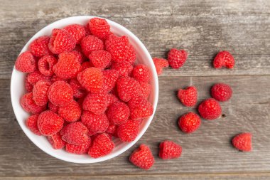 Bir kase ahududu ve ahşap üzerine dökülen böğürtlenlerin yatay üst görüntüsü.