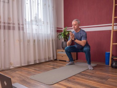 Son sınıf öğrencisi, evde spor yaparken yoga minderinde bacak egzersizi yapıyor.