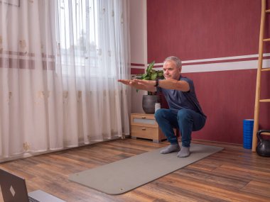 Son sınıf öğrencisi oturma odasındaki yoga minderinde egzersiz yapıyor.