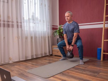 Son sınıf öğrencisi antrenman sırasında yoga minderinde çömelme hareketi yapıyor.