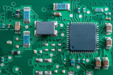 Geniş kare çip ve SMD bileşenlerine sahip yeşil baskılı devre kartının (PCB) aşırı yakın çekimi.