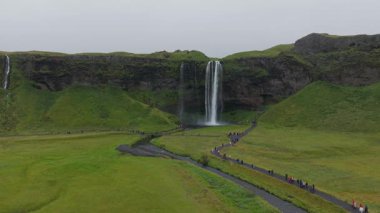 Statik, Seljalandsfoss Şelalesi, İzlanda, bulutlu gökyüzünün altındaki panoramik yeşil vadi