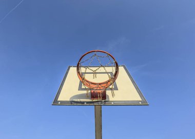 Zincirli bir ağ ve basit bir krem sepet içeren yıpranmış bir basketbol potası..