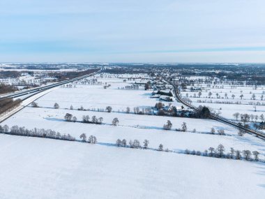 Geometrik alan bölümleri ve dağınık koyu ağaçlarla geniş karlı arazi.