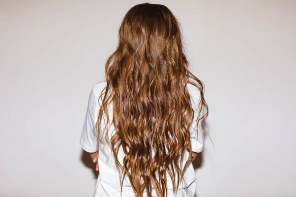 Curly hairdressing for long girl\'s hair. View from the back. View from the back. Focus is at the hair.