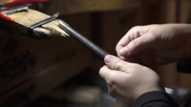 Esnaf atölyesinde aletlerle çalışan bir kadına yakın çekim. Bir alet kullanıyor..