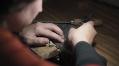 Esnaf atölyesinde aletlerle çalışan bir kadına yakın çekim. Bir alet kullanıyor..