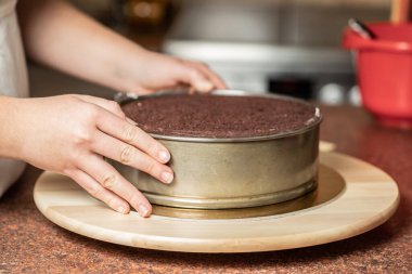 Genç bir kadın mutfağında yeni pişmiş bir pasta süslüyor. Yemek konsepti. Lezzetli.
