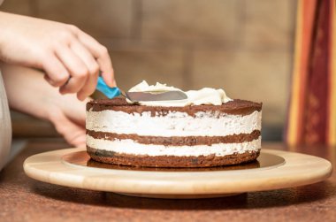 Genç bir kadın mutfağında yeni pişmiş bir pasta süslüyor. Yemek konsepti. Lezzetli.