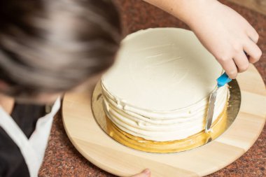 Genç bir kadın mutfağında yeni pişmiş bir pasta süslüyor. Yemek konsepti. Lezzetli.