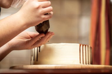 Genç bir kadın mutfağında yeni pişmiş bir pasta süslüyor. Yemek konsepti. Lezzetli.