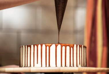 Genç bir kadın mutfağında yeni pişmiş bir pasta süslüyor. Yemek konsepti. Lezzetli.