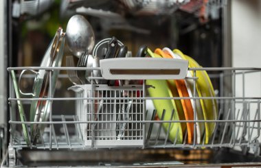 İçinde kirli bulaşıklar olan açık bir bulaşık makinesi. Mutfakta bulaşıkçı.