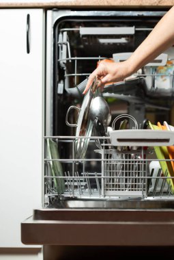 Bulaşıkları makineye koyan genç bir kadın. Mutfakta bulaşıkçı.