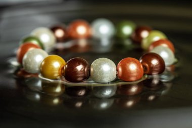 Siyah arka planda eşsiz, renkli bir bilezik. Kadın bilekliği..